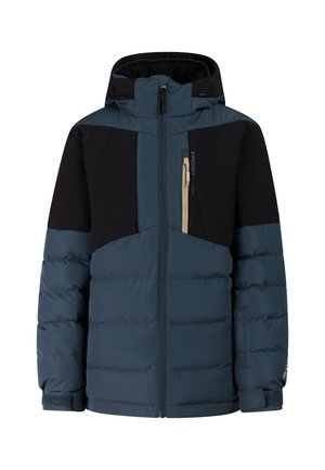 Junge trägt schwarze Mütze, zweifarbige blau-schwarze gesteppte Jacke, schwarze Hose und schwarze Winterstiefel und steht mit den Händen in den Taschen.