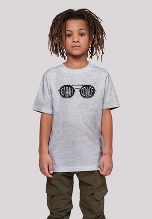 Graues Baumwoll-T-Shirt mit einem schwarzen Grafikdruck von Sonnenbrillen und dem Text "SARAH CONNOR". Kombiniert mit olivgrünen Cargo-Hosen.
