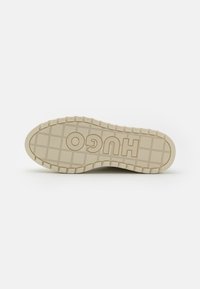 Suela de zapato de goma color crema con un patrón de cuadrícula texturizado. Presenta un audaz logo "HUGO" y un diseño de borde elevado y duradero para mayor tracción.