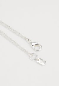 Colar de corrente em prata com fecho tipo lagosta, elo circular e uma placa retangular com detalhe gravado. Textura suave e acabamento brilhante.