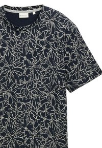 Chemise à manches courtes marine avec un motif floral blanc, col rond et texture de tissu douce. Design décontracté adapté aux temps chauds.