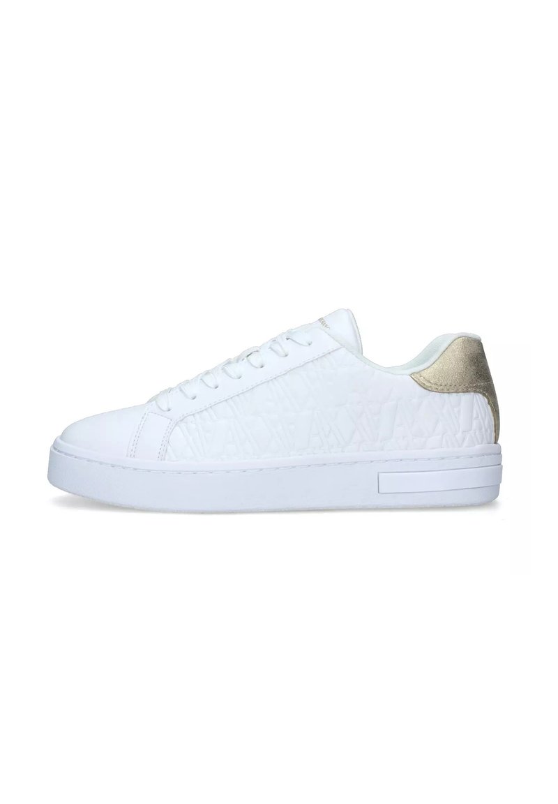White sneakers with a textured surface, round toe, and flat sole. Features a subtle metallic gold heel accent and white laces.