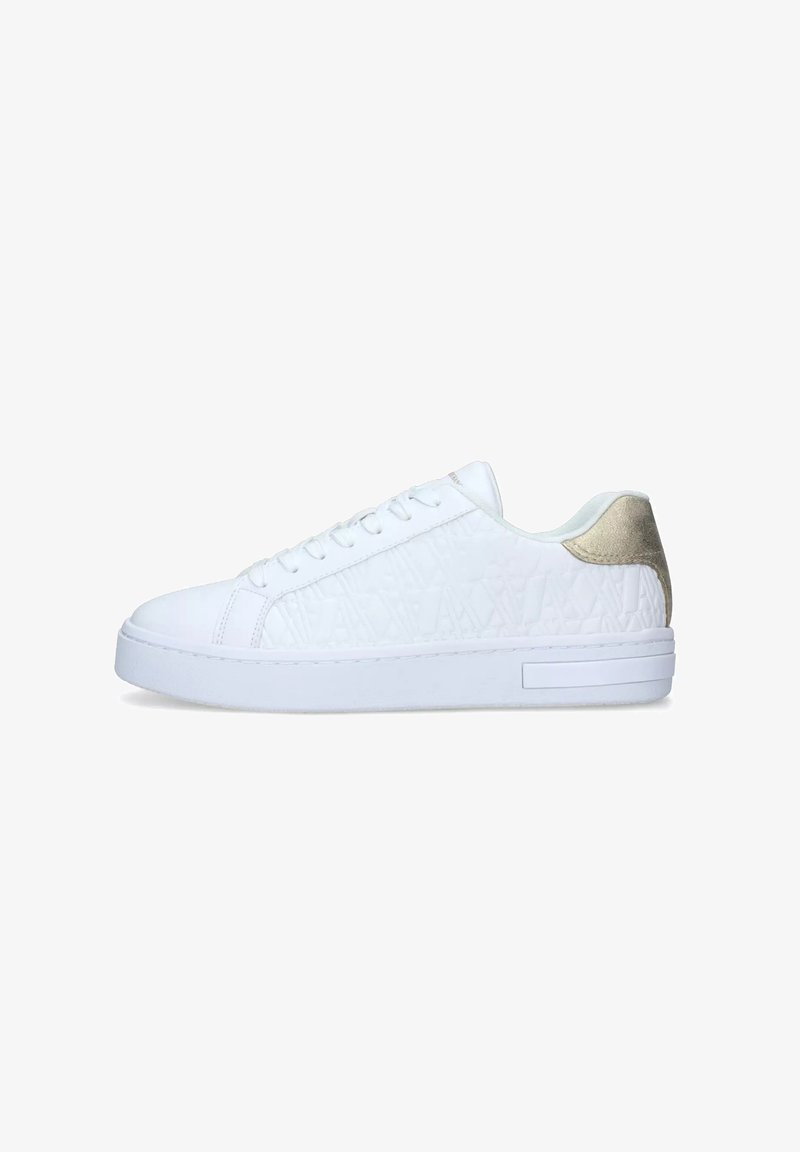 White sneakers with a textured surface, round toe, and flat sole. Features a subtle metallic gold heel accent and white laces.