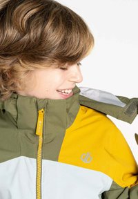 Bunte Jacke mit grünen, gelben und weißen Paneelen. Hoher Kragen mit Reißverschluss und Klettverschluss-Akzenten. Weicher, strukturierter Stoff. Logo angezeigt.