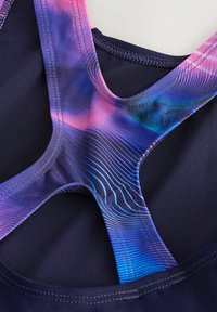 Sport-BH mit einem dunklen Marineblau als Grundfarbe, ausgestattet mit einem lebhaften pink-blauen Batikmuster an den Trägern, das glattes synthetisches Material und ein elegantes Design präsentiert.