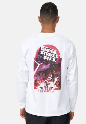 Langærmet hvid t-shirt med et farverigt grafisk motiv af "The Empire Strikes Back" på ryggen, der viser fremtrædende figurer og rumskibs grafik.