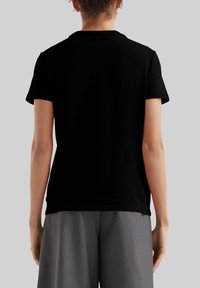 Zwarte T-shirt met korte mouwen en een ronde hals, een gladde textuur en een aangesloten silhouet, gedragen met hoge, grijze broeken.