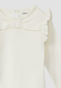 Kremowa bluzka z długim rękawem, z falbanami na ramionach i kokardą przy dekolcie, z zapięciem z tyłu na kluczyk.