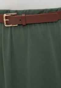Πράσινη, απαλή υφασμάτινη φούστα με ελαστική μέση. Διαθέτει καφέ ζώνη με χρυσή μεταλλική αγκράφα.