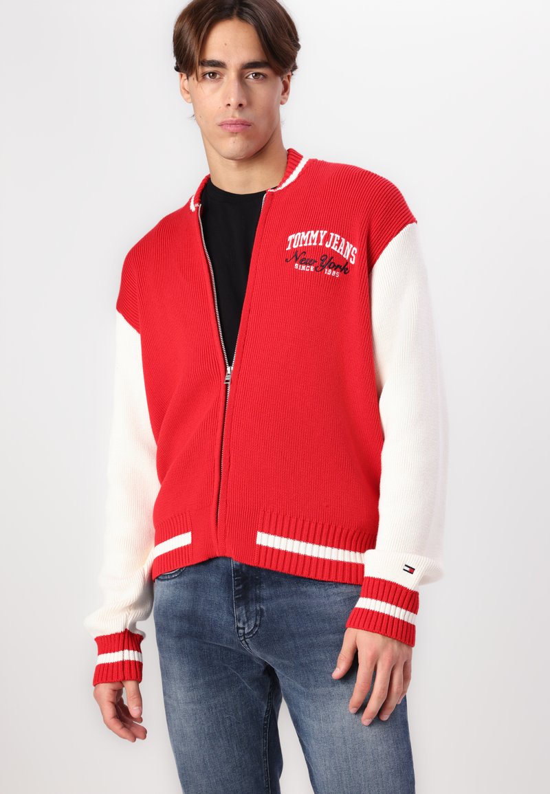 Ribbed Zip-Up-Cardigan in Rot und Weiß mit kontrastierenden Ärmeln und gestreiften Bündchen; mit gesticktem Logo auf der Brust; glatte Textur.