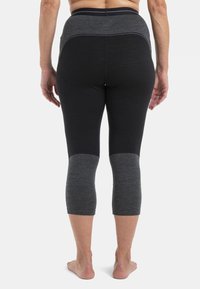 Mustat ja harmaat capri-legginssit korkealla vyötäröllä, jossa on teksturoitu kangas ja värilohkotoiminto polvissa.