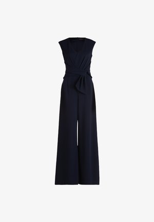 Combinaison sans manches bleu marine avec un décolleté en V profond, une taille froncée et une coupe évasée. Tissu doux avec un détail à nouer à la taille.