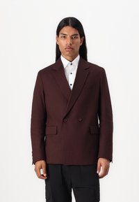 Burgundy dubbelknäppt kavaj, texturerad tyg, slagkragar, framfickor, bärs över en vit skjorta med blå knappar, slim fit-design.