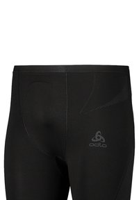 Leggings sportivi neri con una texture liscia, vita elasticizzata e dettagli in rete sui lati. Logo Odlo in grigio riflettente nella parte anteriore.