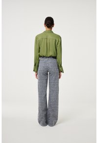 Groene satijnen shirt met een kraag en knoopmanchetten, gecombineerd met wijde, gemusterde grijze broek met zakken en een ontspannen pasvorm.