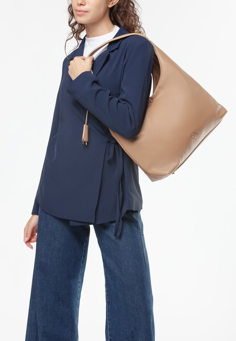 Beige leren hobo-tas met een ronde vorm, een soepele textuur en een lange schouderriem. Voorzien van een ritssluiting en een subtiele logodetail.