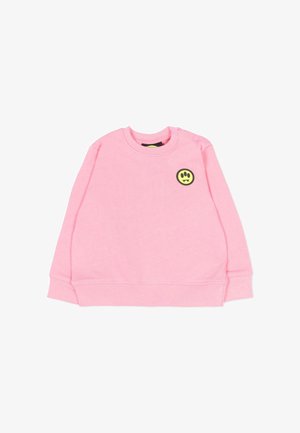 Roze sweater met lange mouwen en een ronde hals, met een kleine gele en zwarte smiley-patch op de bovenste linkerborst en drukknoopjes op de schouder.