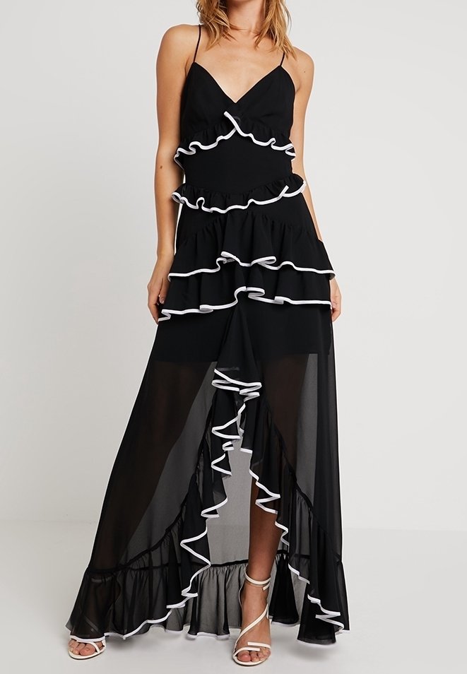 Schwarzes Maxikleid mit durchscheinenden Schichten, versehen mit weißen Rüschen entlang der Kanten und verstellbaren Spaghetti-Trägern. Weit schwingender Saum und entspannte Passform.