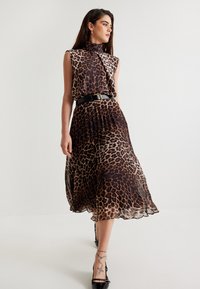 Abito con stampa leopardata realizzato in tessuto trasparente, con collo alto, design senza maniche, gonna a pieghe e una cintura nera in vita.