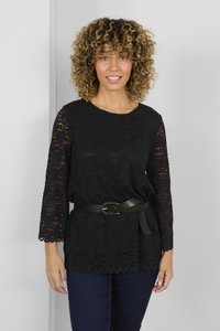 Black lace top with 3/4 sleeves, round neckline, and scalloped hem. Worn with a black belt featuring a round buckle. Fitted pants.