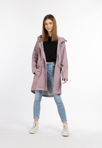 Ljuslila vattentät parka med dragsko huva, två framfickor, grå foder och silverfärgade tryckknappar. Bärs över blå smala jeans.