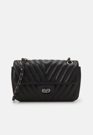 Bolso de mano de cuero negro acolchado con cierre giratorio de tono plateado y correa de cadena sobre fondo liso.