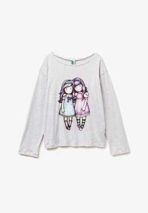 Světle šedá košile s dlouhým rukávem s grafikou dvou dívek v pastelových šatech, jedna v modré s čelenkou, druhá v růžové se pruhovanými ponožkami, stojící vedle sebe.