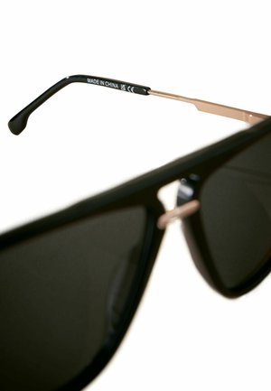 Crne sunčane naočale s tamnim lećama, metalnim detaljima i mat crnim okvirom. Jedna drška ima natpis "MADE IN CHINA".