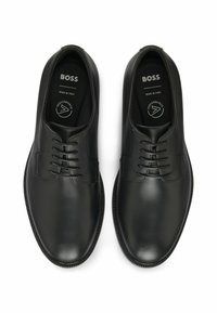 Scarpe nere in pelle con finitura liscia, design con lacci, punta rotonda e suole in gomma texturizzata. Marchio sulle solette. Made in Italy.