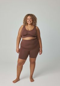 Brązowy, bezszwowy komplet sportowy dwu-częściowy, składający się z dopasowanego krótkiego topu i szortów z wysokim stanem, charakteryzujący się gładką teksturą i minimalistycznym wzornictwem.