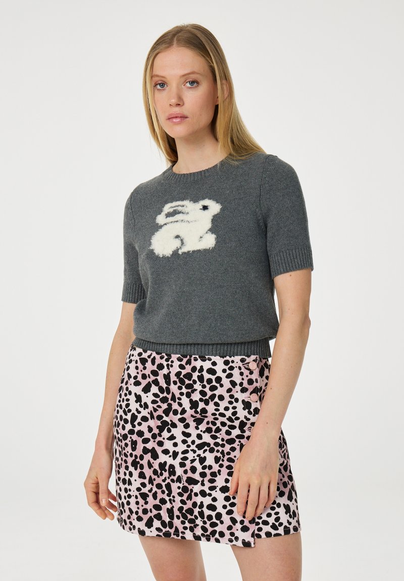 Grijze gebreide trui met korte mouwen, versierd met een ontwerp van een witte pluizige konijn, gecombineerd met een roze rok met zwarte en roze spetterpatronen.