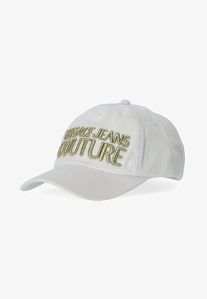 Witte baseballpet gemaakt van stof, met verhoogde gouden borduursel van "VERSACE JEANS COUTURE" aan de voorkant en een gebogen rand.
