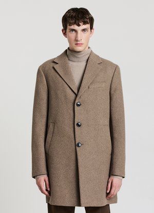 Cappotto di lana marrone con rever a lancia, tre bottoni neri, tasche laterali e taschino sul petto, indossato sopra un dolcevita chiaro.