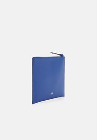 Niebieska skórzana saszetka o gładkiej fakturze, w kwadratowym kształcie, z górnym zamknięciem na zamek i małym ozdobnym uchwytem. Minimalistyczny design bez widocznego logo.