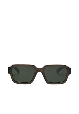 Prostokątne soczewki w ciemnozielonym odcieniu z grubą, ciemnobrązową przezroczystą plastikową oprawą okularów przeciwsłonecznych na białym tle.