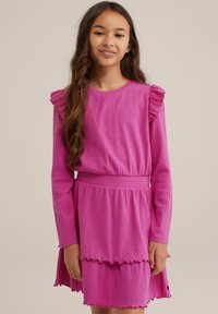 Lila långärmad klänning med volangdetaljer, midja med dragsko och lager med kjol som har en vågformad fåll. Mjuk ribbad textur.