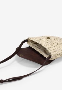 Bolso bandolera de paja trenzada con base de cuero marrón, que cuenta con un cierre magnético y un interior forrado. Incluye correa ajustable.