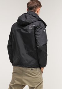 Czarna lekka kurtka z kapturem, wykonana z wodoodpornego materiału. Posiada branding na plecach oraz elastyczne mankiety.