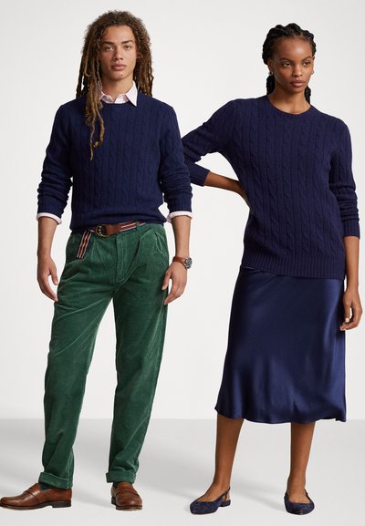 Pull en maille côtelée bleu marine et pantalons en velours côtelé verts à gauche ; jupe en satin bleu marine et ballerines à droite ; tissus texturés, coupe décontractée.