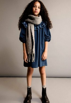 Denim dress with puff sleeves and embroidered collar, gray scarf, and black ankle boots with zipper detail. Light gray background.