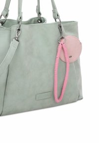 Sac fourre-tout vert menthe en matériau synthétique lisse, doté de quincaillerie argentée, d'une étiquette ronde rose et d'un accent de poignée texturée rose.