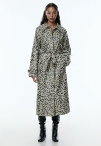 Beige en zwarte luipaardprint trenchcoat, met een kraag, een ceintuur in de taille, lange mouwen en een lengte tot onder de knie.