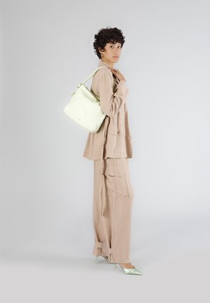Lys grøn læder spandebag med flettet håndtag, båret over et beige linned-outfit med store lommer og skræddersyet pasform, suppleret med mintfarvede hæle.