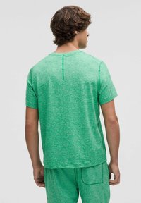Grünes, kurzärmliges, strukturiertes T-Shirt mit Rundhalsausschnitt, das ein dezentes Melange-Muster und eine vertikale Nahtdetails auf der Rückseite aufweist.