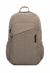 Mochila Thule en tela beige claro, con un bolsillo frontal con cremallera, correas ajustables y un asa superior para facilitar su transporte.