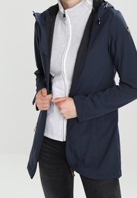 Marineblaue wasserdichte Jacke mit Kapuze, durchgehendem Reißverschluss und verstellbaren Bündchen über einer hellgrauen Innenlage, die ein schlankes, tailliertes Design aufweist.