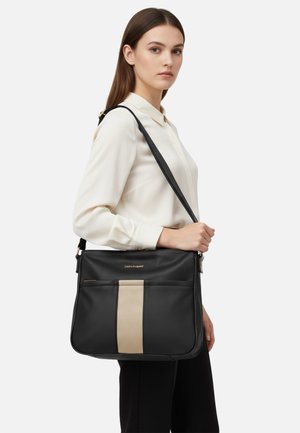 Borsa nera con una texture traforata, caratterizzata da una striscia verticale beige. Tracolla regolabile e dettaglio logo dorato sul davanti.