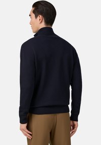 Tumši zils adīts džemperis ar augstu apkakli, ribotām piedurknēm un jostu, ar gludu tekstūru un pieguļošu dizainu.