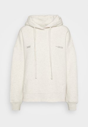 Cremefarbener Kapuzenpullover mit Fronttasche, Kordelzug und kleinem aufgedrucktem Text auf der Brust und nahe der Schulter.