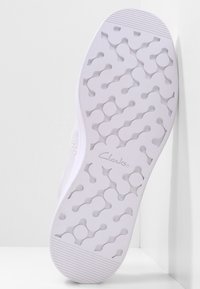 Semelle de chaussure en caoutchouc blanche avec un motif ondulé texturé, avec le logo "Clarks" en relief. Fini lisse avec un design à bout rond.